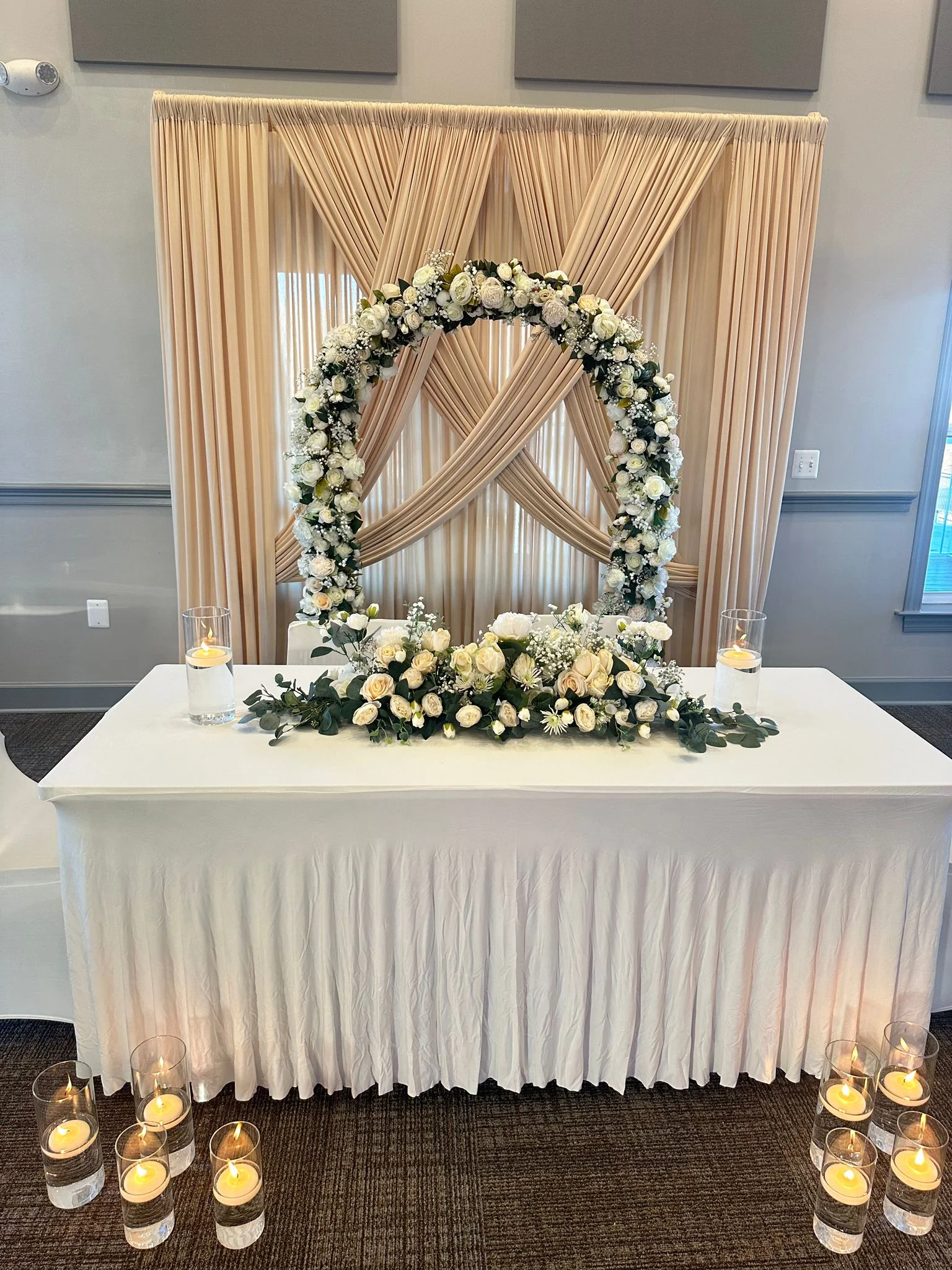 A draped floral head-table backdrop styled for a wedding